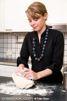 A young woman makes bread on the counter at ho...
